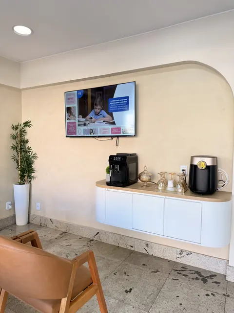 Cantinho do café da recepção, com máquina de espresso, televisão e poltrona